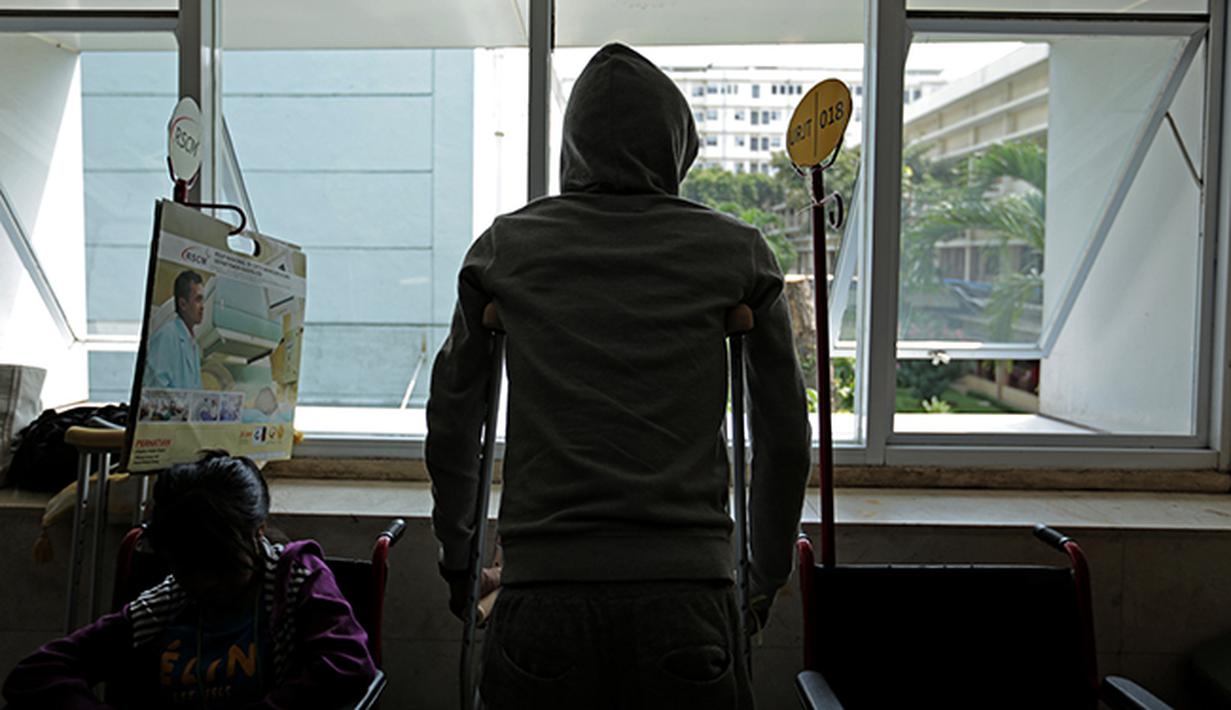 Alfin Tuasalamony membuang rasa jenuh menanti giliran waktu berkonsultasi dengan dokter. (Bola.com/Peksi Cahyo)