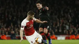 Aaron Ramsey mencoba menghentikan Gerzino Nyamsi pada leg kedua,babak 16 besar Liga Europa yang berlangsung di Stadion Emirates, London, Jumat (15/3). Arsenal menang 3-0 atas Rennes. (AFP/Ian Kington)