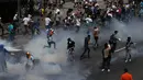 Para demonstran menghindari tembakan gas air mata saat bentrokan terjadi di Caracas, Venezuela, (6/4). Lemparan batu, tembakan gas air mata hingga meriam air warnai bentrokan demonstran anti-Maduro dan polisi di Venezuela. (AP Photo / Fernando Llano)
