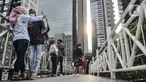 Warga berfoto di jembatan penyeberangan orang (JPO) tanpa atap di kawasan Sudirman, Jakarta, Minggu (4/4/2021). JPO tanpa atap masih menjadi wisata alternatif warga ibu kota dalam menghabiskan waktu akhir pekan untuk berfoto-foto dengan latar belakang gedung perkantoran (merdeka.com/Iqbal S Nugorho