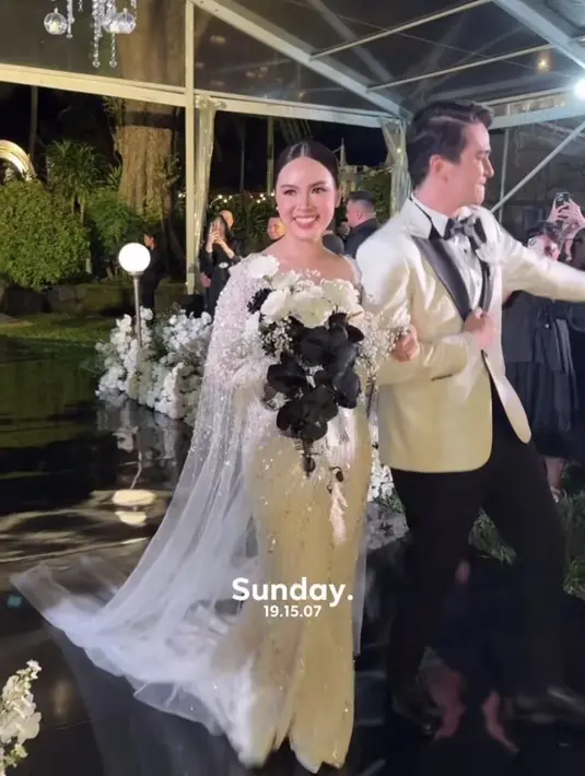 Untuk resepsi pernikahan, keduanya tampil serba putih. Sambil membawa buket bunga mawar putih dan hitam, Marcella tampil anggun mengenakan gaun putih panjang dihiasi dengan beads yang blink-blink serta cape belakang yang menyapu lantai. [@yessicatiano]