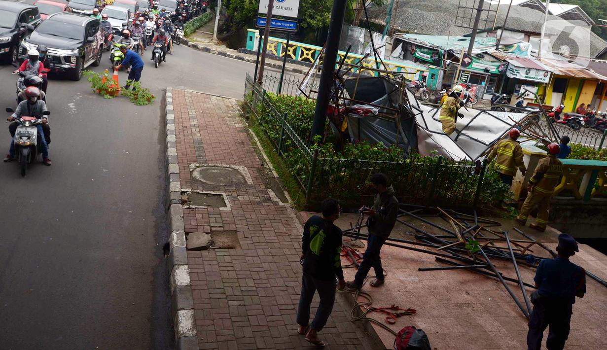 Kondisi lalu lintas saat petugas pemadam kebakaran memotong rangka reklame yang roboh di Jalan Soepomo, Jakarta, Sabtu (28/5/2022). Hujan disertai angin kencang pada pagi tadi membuat papan reklame roboh sehingga membuat kemacetan arus lalu lintas di jalan tersebut. (merdeka.com/Imam Buhori)