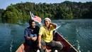 Pemburu madu Malaysia tradisional Zaini Abdul Hamid (kanan) dan Abdul Samad Ahmad menaiki perahu usai mengumpulkan madu dari sarang lebah di hutan Ulu Muda di Sik, timur laut negara bagian Malaysia, Kedah (12/3). (AFP Photo/Manan Vatsyayana)