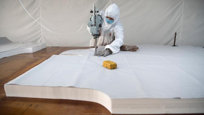 Pekerja memotong bahan untuk digunakan membuat pakaian antivirus di pabrik garmen Zhejiang Ugly Duck Industry, di Wenzhou, 28 Februari 2020. Wabah virus corona di China membuat produsen pakaian itu mulai memproduksi baju hazmat yang banyak diburu orang untuk melindungi dirinya. (NOEL CELIS/AFP)