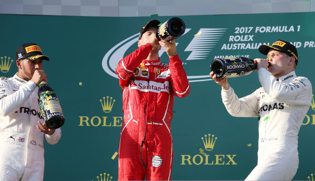(Ki-ka) Pembalap Mercedes, Lewis Hamilton, pembalap Ferrari, Sebastian Vettel dan pembalap Mercedes, Valtteri Bottas meminum sampanye di atas podium balapan GP Australia di Sirkuit Albert Park, Melbourne, Minggu (26/3). (AP Photo/Rick Rycroft)