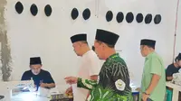 Pengasuh Ponpes Bumi Damai Al Mustawa, KH Muzayin ketika memperlihatkan kepada Anggota DPRD Jawa Tengah, H Abdullah Aminuddin saat santri alumni pesantren setempat memproses pembuatan peci hitam. (Liputan6.com/Ahmad Adirin)