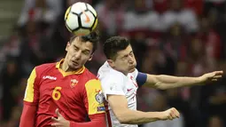 Striker Polandia, Robert Lewandowski, duel udara dengan bek Montenegro, Zarko Tomasevic, pada laga Kualifikasi Piala Dunia 2018 di Stadion National, Warsawa Minggu (8/10/2017). Polandia menang 4-2 atas  Montenegro. (AP/Alik Keplicz)