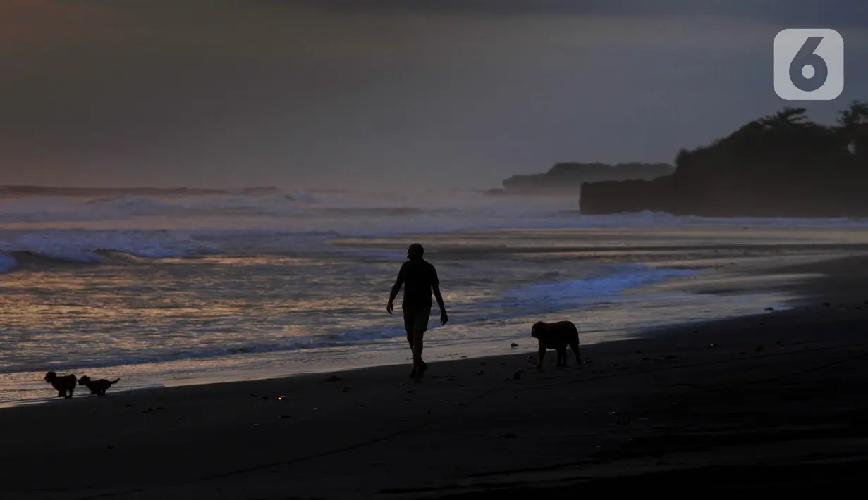 Warga membawa anjingnya berjalan di tepi Pantai Pasut, Tabanan, Bali, Sabtu (4/9/2021). Menteri Pariwisata dan Ekonomi Kreatif Sandiaga Uno menyebut okupansi di berbagai destinasi wisata di Bali masih mengalami kontraksi signifikan. (merdeka.com/Arie Basuki)