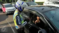 Petugas kepolisian memberikan informasi kepada pengendara mobil terkait penerapan sistem ganjil genap di Bundaran Senayan, Jakarta, Rabu (27/7). Penerapan ganjil genap yang dimulai pada hari ini masih tahap uji coba. (Liputan6.com/Gempur M Surya)