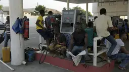 Warga duduk di dekat nozzle saat antre mengisi bahan bakar di sebuah SPBU di Lagos, Nigeria,Selasa (1/12). Krisis bahan bakar yang telah melanda Nigeria dalam beberapa bulan terakhir menyebabkan antrean panjang di SPBU. (AFP PHOTO/PIUS Utomi EKPEI)