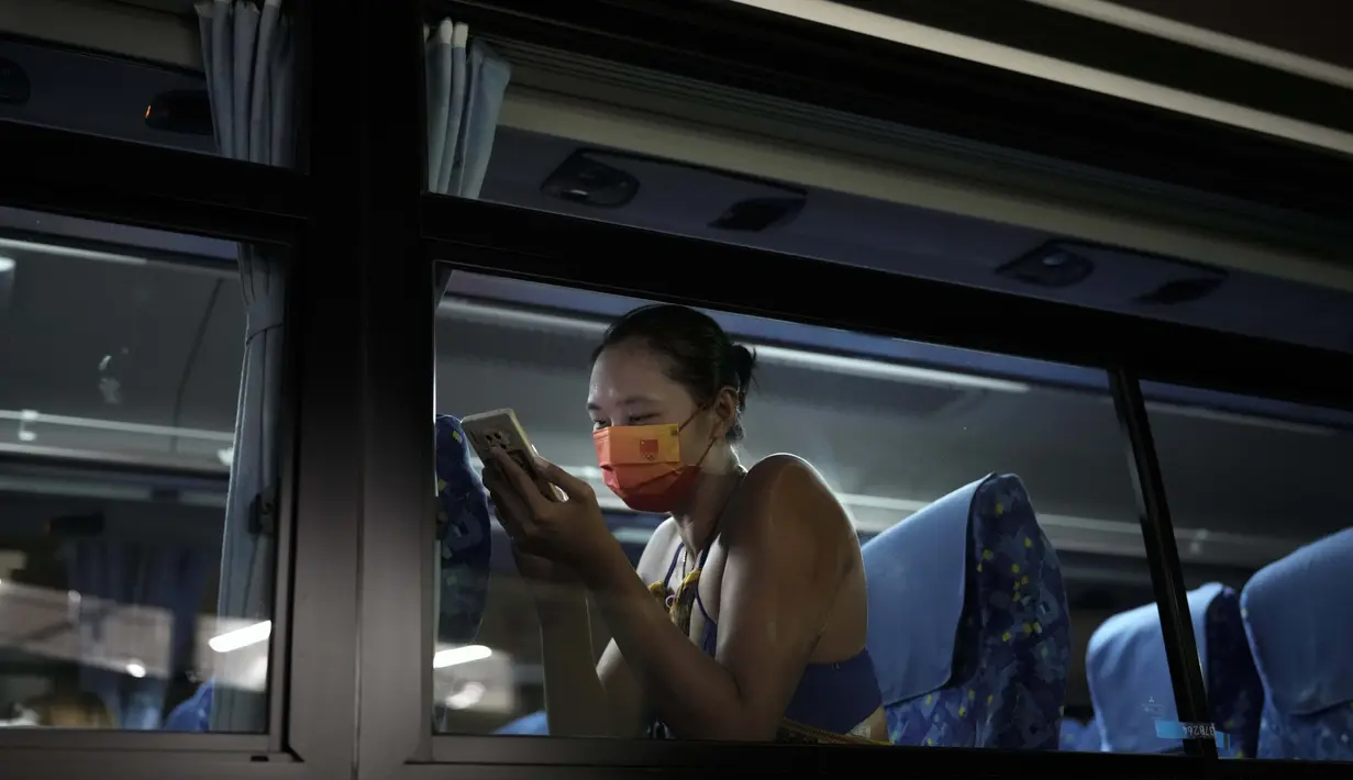 Wang Fan asal Tiongkok, berinteraksi dengan telepon selular saat berada di dalam bus usai pertandingan voli pantai putri Olimpiade Tokyo 2020 melawan Brasil, Selasa (27/7/2021). (Foto: AP/Felipe Dana)