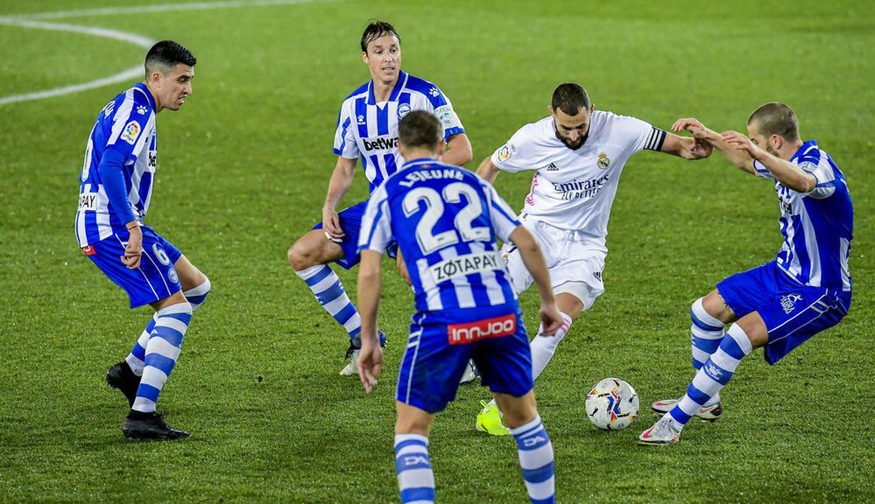 Striker Real Madrid, Karim Benzema, berusaha melewati pemain Alaves pada laga Liga Spanyol di Stadion Mendizorroza, Sabtu (23/1/2021). Real Madrid menang dengan skor 4-1. (AP/Alvaro Barrientos)