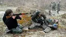 Warga sipil berlatih menembak sementara rekannya melakukan pengobatan prajurit yang terluka saat mengikuti sesi pelatihan militer oleh Right Sector dekat Lviv, Ukraina, 24 Februari 2023. (AP Photo/Mykola Tys)