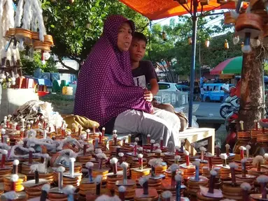 Pedagang menunggu pembeli saat berjualan pelita di Jalan Sam Ratulangi, Kota Gorontalo, Rabu (22/5/2019). Sejumlah pedagang menjual pelita dari botol bekas untuk menyambut perayaan Tumbilotohe atau malam pasang lampu yang digelar tiga hari menjelang Idul Fitri di Gorontalo. (Liputan6.com/Arfandi Ibr