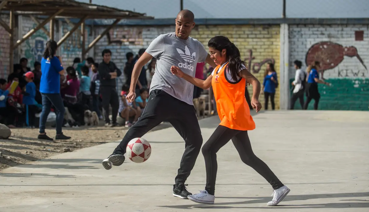 Mantan pemain bola Juventus, David Trezeguet bersiap menendang bola saat bermain bersama anak-anak di komunitas San Pablo Mirador, Peru (13/7). (AFP Photo/Ernesto Benavides)
