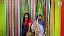 Dua wisatawan berpose di balik pita di kampung warna-warni, Kelurahan Kesatrian, Kota Malang, Minggu (5/11). Lukisan di kampung tersebut melibatkan komunitas mural dan seniman. (Liputan6.com/Fery Pradolo)