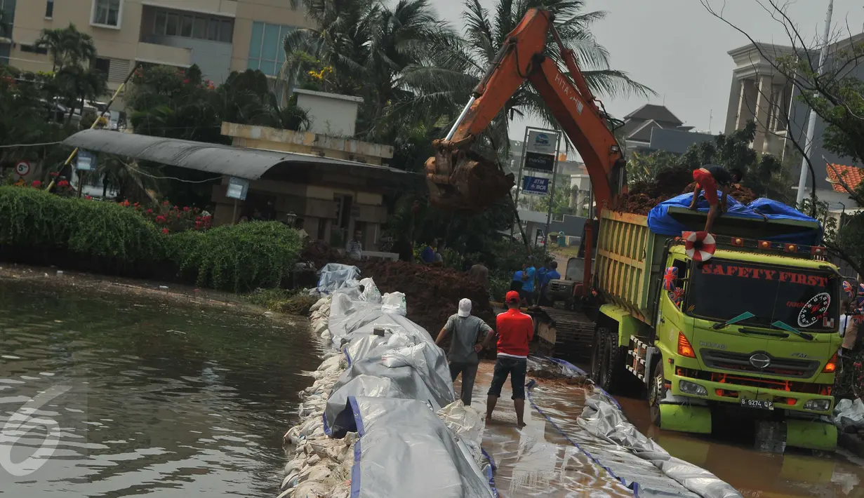 Alat berat dikerahkan untuk membuat tanggul untuk mencegah banjir di kawasan Perumahan Pantai Mutiara, Jakarta, Sabtu (4/6). Akibat tanggul jebol kawasan tersebut tergenang dengan ketinggian 50-60 sentimeter. (Liputan6.com/Gempur M Surya)