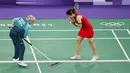 Seorang volunter sedang memberishkan keringan pebulu tangkis putri Thailand, Ratchanok Intanon saat pertandingan grup Olimpiade Paris 2024 melawan atlet Belgia, Lianne Tan di Porte de la Chapelle Arena, Paris, Prancis pada 30 Juli 2024. (AFP/Luis Tato)