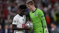 Kiper Inggris Jordan Pickford (kanan) menyemangati rekan setimnya Bukayo Saka saat adu penalti dengan Italia pada pertandingan Euro 2020 di Stadion Wembley, London, Inggris, Minggu (11/7/2021). Italia menang 3-2 lewat adu penalti usai bermain imbang 1-1. (Laurence Griffiths/Pool via AP)