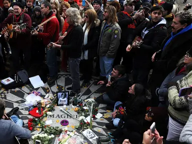Sejumlah orang, penggemar dari grup band The Beatles berkumpul sambil bernyanyi saat memperingati 36 tahun kematian John Lennon di New York, AS (8/12). Mereka berkumpul di sebuah tempat yang bernama Strawberry Fields. (Reuters/Mark Kauzlarich)