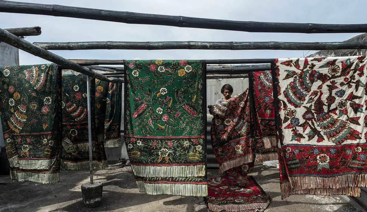 Seorang pekerja menjemur batik di pabrik "batik" kain tradisional Indonesia di Sidoarjo, Jawa Timur (12/11/2019). UNESCO menetapkan batik sebagai karya agung lisan dan warisan budaya takbenda kemanusiaan. (AFP Photo/Juni Kriswanto)