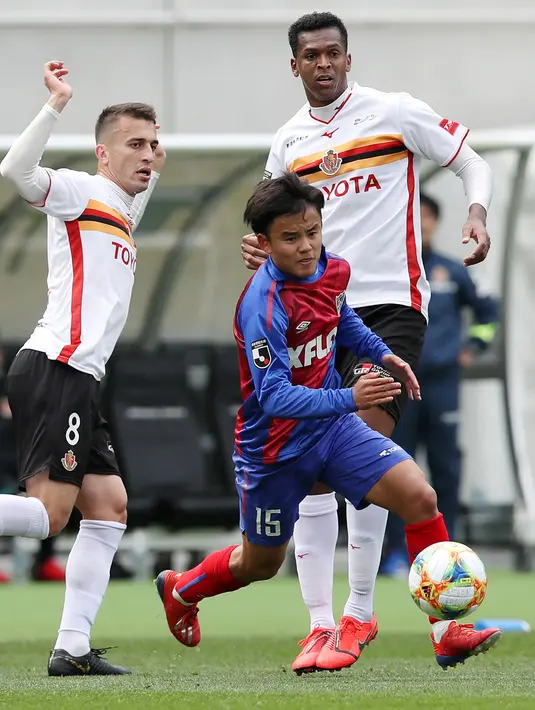 Gelandang Jepang Takefusa Kubo menggiring bola usai melewati dua pemain Nagoya Grampus Eight di Tokyo (13/3/2019). Kubo sempat mengenyam pendidikan di akademi Barcelona pada 2011 hingga 2015 silam. (AFP Photo/Jiji Press)