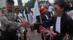 Aksi simpatik Peradi saat berunjuk rasa dengan membagikan bunga pada petugas kepolisian yang menjaga jalannya aksi, Jakarta, Kamis (11/9/2014) (Liputan6.com/Johan Tallo)