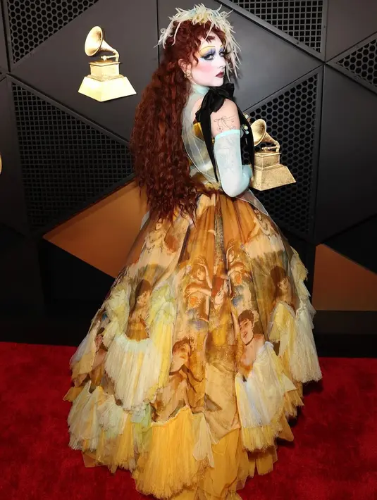 Kian stand out, Roan memadukan riasannya dengan gaun ikonik tersebut, menampilkan makeup khas boneka porselen dengan kombinasi warna biru dan emas pada mata serta lipstik cherry yang dalam.  [@genesiswbb].