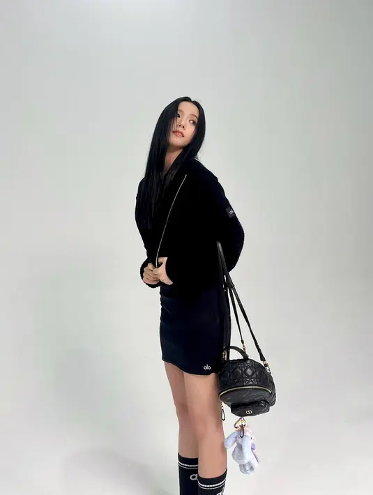 Gayanya disempurnakan dengan mini skirt yang serasi dan berwarna sama-sama hitam. Ia padukan lagi dengan kaus kaki hitam tinggi dan alas kaki cokelat. [Foto: Instagram/sooyaaa__]