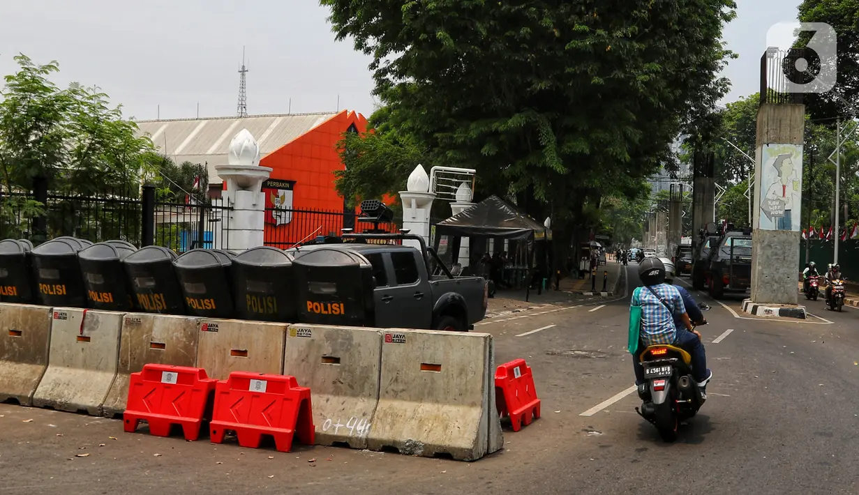 Pengendara motor melintas dekat tameng-tameng petugas kepolisian yang diletakkan di sekitar kompleks Parlemen Gedung DPR/MPR, Senayan, Jakarta, Rabu (16/10/2019). Penjagaan Komplek Parlemen diperketat untuk Pelantikan Presiden dan Wakil Presiden periode 2019 – 2024. (Liputan6.com/Johan Tallo)
