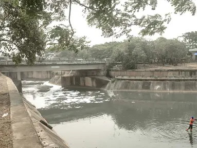 Pekerja membersihkan sampah yang mengotori aliran Kanal Banjir Timur (KBT) di Jakarta, Sabtu (15/9). Banyaknya limbah rumah tangga dan limbah industri menyebabkan kanal pengendali banjir tersebut selalu tercemari sampah. (Liputan6.com/Immanuel Antonius)