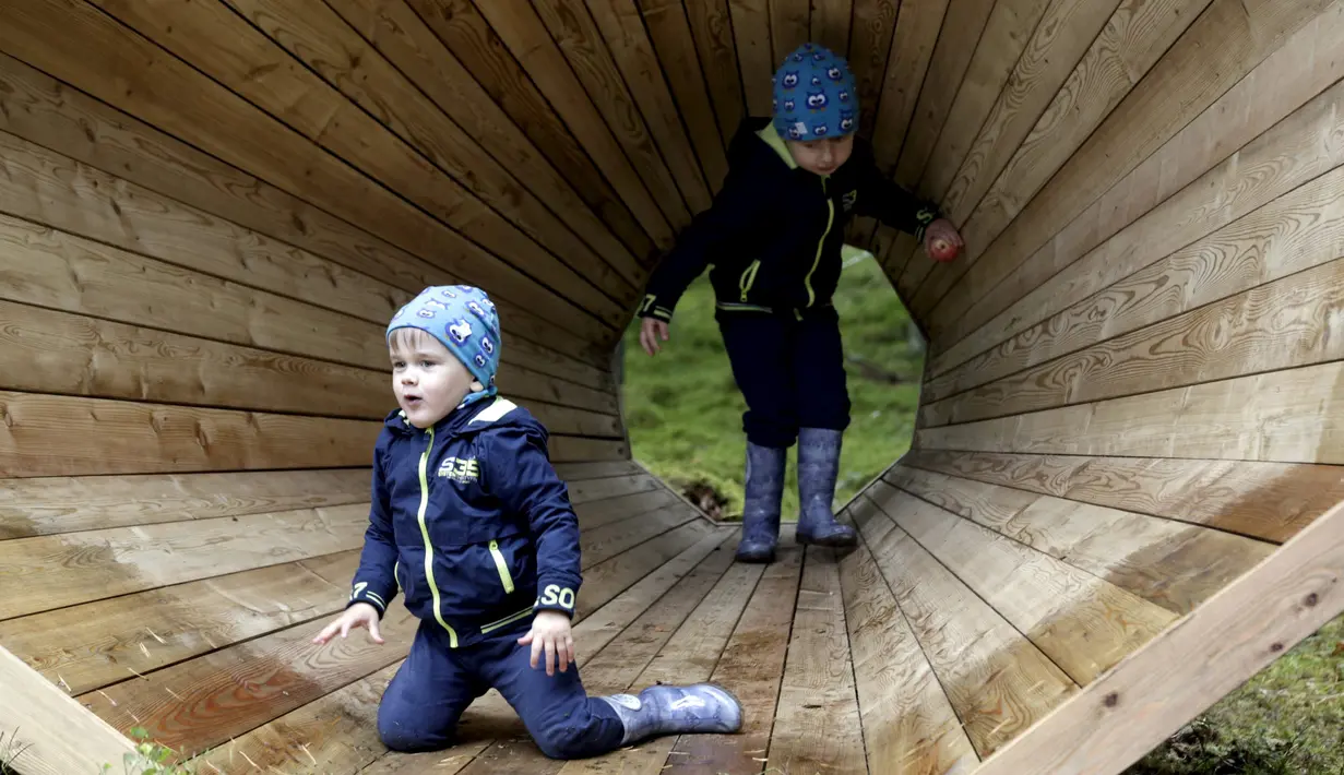 Sejumlah anak bermain di megafon raksasa dari kayu buatan sekelompok mahasiswa arsitektur interior di dalam hutan Estonia, 28 September 2015. Megafon ini dibuat untuk mendengarkan suara hutan dan mahluk yang tinggal di dalamnya. (REUTERS/Ints Kalnins)