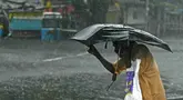 Seorang pejalan kaki menyeberangi jalan yang tergenang air setelah hujan lebat di Chennai, kawasan Teluk Benggala, Timur India pada 4 Desember 2023. (R. Satish BABU/AFP)