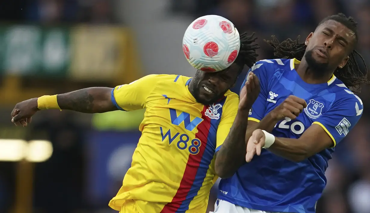 <p>Penyerang Everton Alex Iwobi berebut bola dengan gelandang Crystal Palace Jeffrey Schlupp pada laga tunda pekan ke-33 Liga Inggris di Goodison Park, Jumat (20/5/2022) dini hari WIB. Everton dipastikan selamat dari zona degradasi usai menang dramatis 3-2 atas Crystal Palace. (AP Photo/Jon Super)</p>
