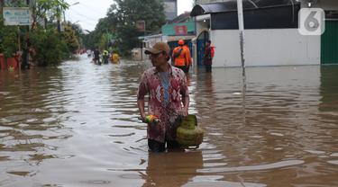 Warga berjalan melewati banjir di Perumahan Ciledug Indah 1 dan 2, Kota Tangerang, Banten, Sabtu (16/7/2022). Banjir tersebut merendam ratusan rumah di dua titik-titik tersebut dengan ketinggian yang bervariasi, mulai dari 50 sentimeter, hingga 1,5 meter. (Liputan6.com/Angga Yuniar)