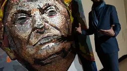 Seniman Inggris Daniel Green memberi keterangan lukisan Presiden AS Donald Trump yang dibuat oleh dirinya dan Daria Marchenko dengan menggunakan rangkaian koin di Akademi St George di New York (30/1). (AFP Photo/Don Emmert)