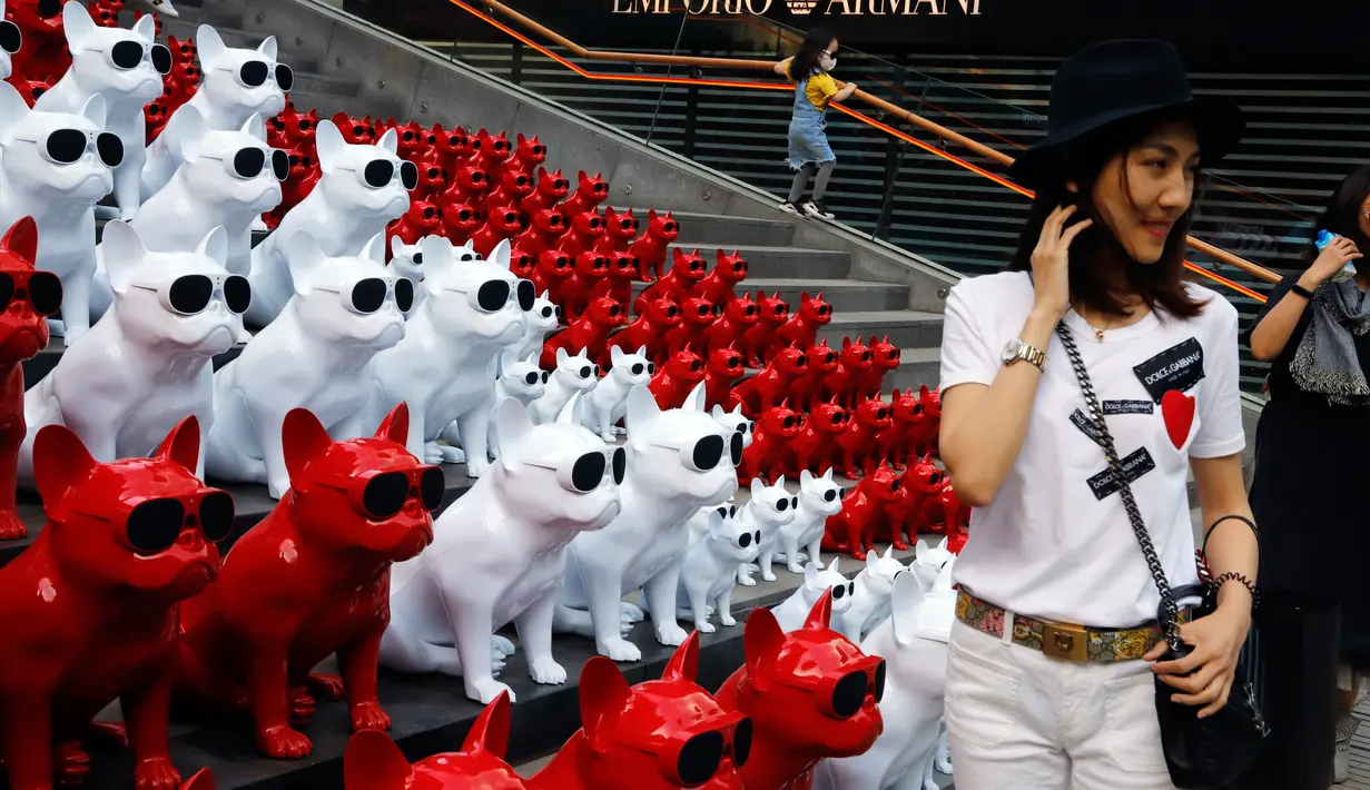 Seorang wanita berpose di depan speaker audio yang berbentuk anjing mengenakan kacamata di distrik perbelanjaan di Beijing, China (3/5). (AP Photo / Ng Han Guan)