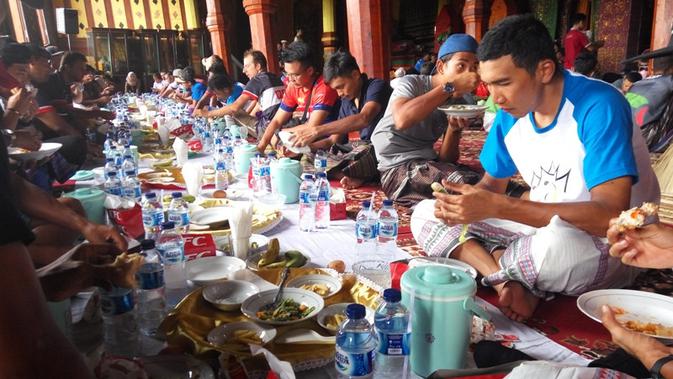 Pembalap Tour de Singkarak 2018 mencoba tradisi makan bajamba di Istana Basa Pagaruyung selepas etape III, Selasa (6/11/2018). (Bola.com/Rizki Hidayat)