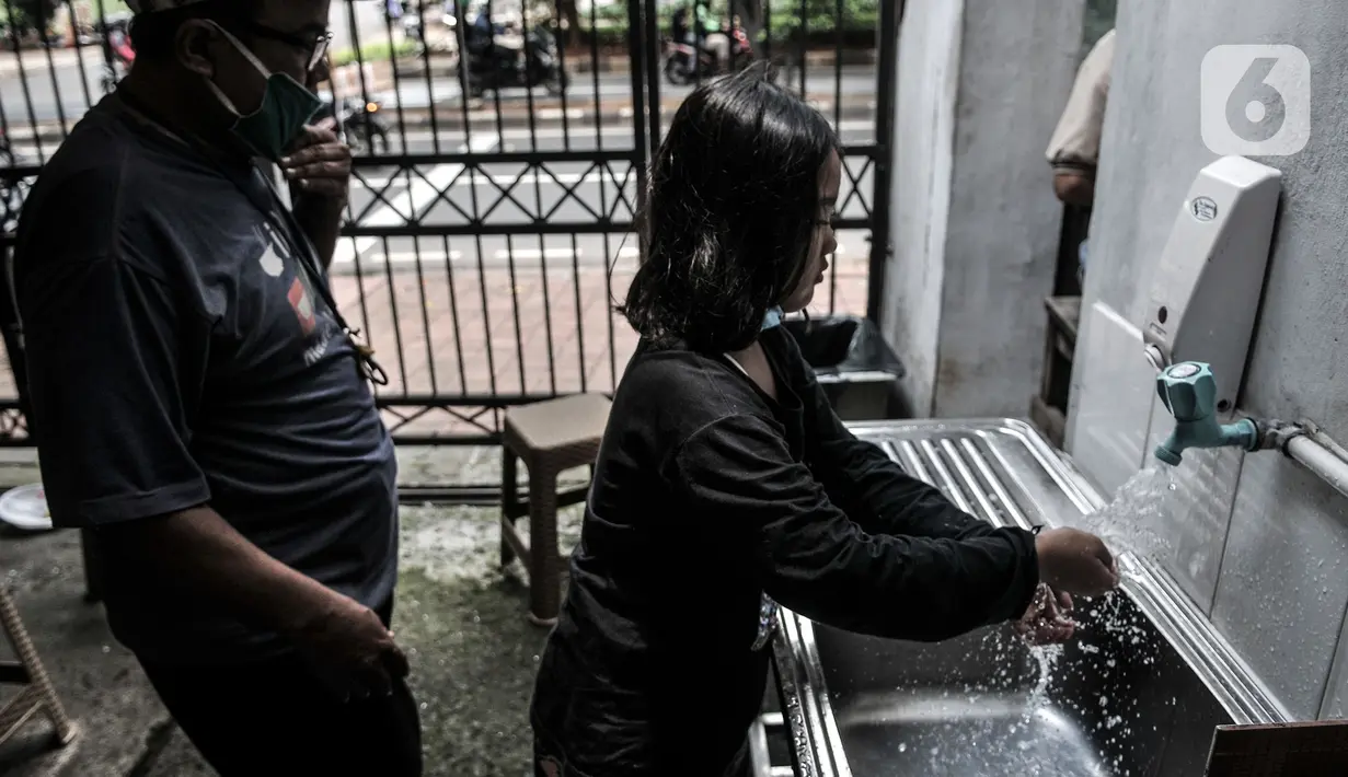 Warga mencuci tangan sebelum mengambil layanan makan gratis di Jalan Basuki Rachmat, Cipinang Muara, Jakarta, Senin (8/3/2021). Sebagian besar yang datang mayoritas berprofesi kuli bangunan, pengamen, petugas taman kota hingga pengemudi ojek online. (merdeka.com/Iqbal S Nugroho)
