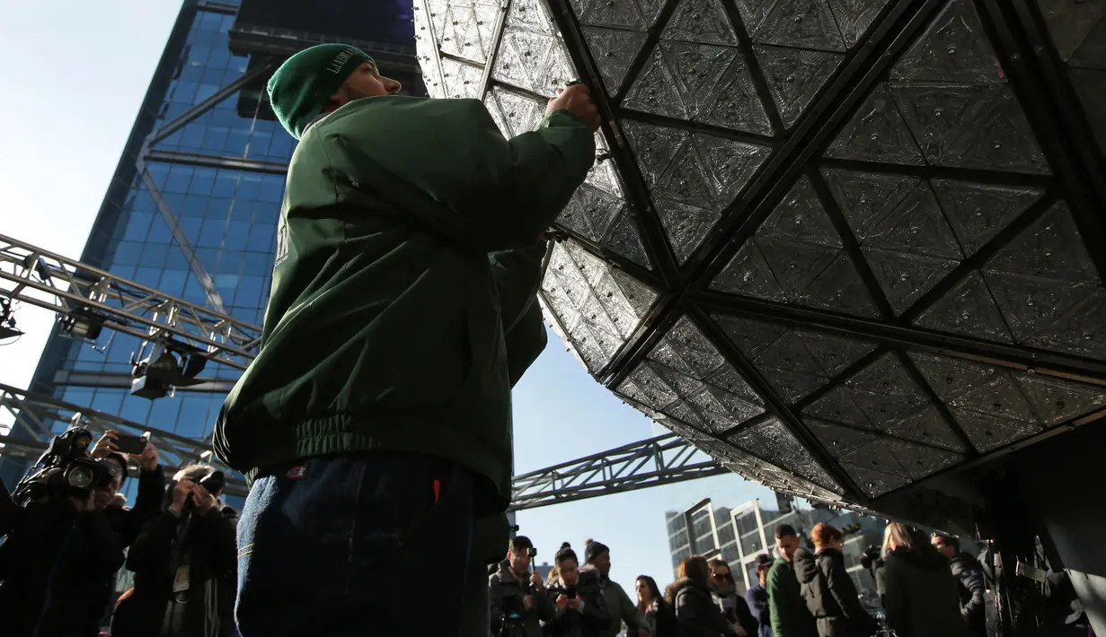 Pekerja memasang kristal berbentuk segitiga pada bola raksasa di atas sebuah gedung di Times Square, New York, Kamis (27/12). Menyaksikan bola kristal raksasa adalah tradisi yang tidak terlewatkan setiap perayaan tahun baru sejak 1904. (AP/Seth Wenig)
