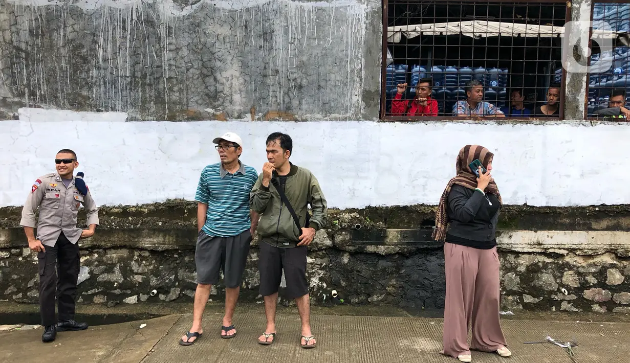 Warga bersama personel kepolisian berkumpul di bantaran Sungai Ciliwung, Jakarta, Selasa (25/2/2020). Adanya seorang warga yang hanyut saat berenang di tengah luapan Sungai Ciliwung tersebut mengundang perhatian warga serta petugas yang mencari keberadannya. (Liputan6.com/Immanuel Antonius)