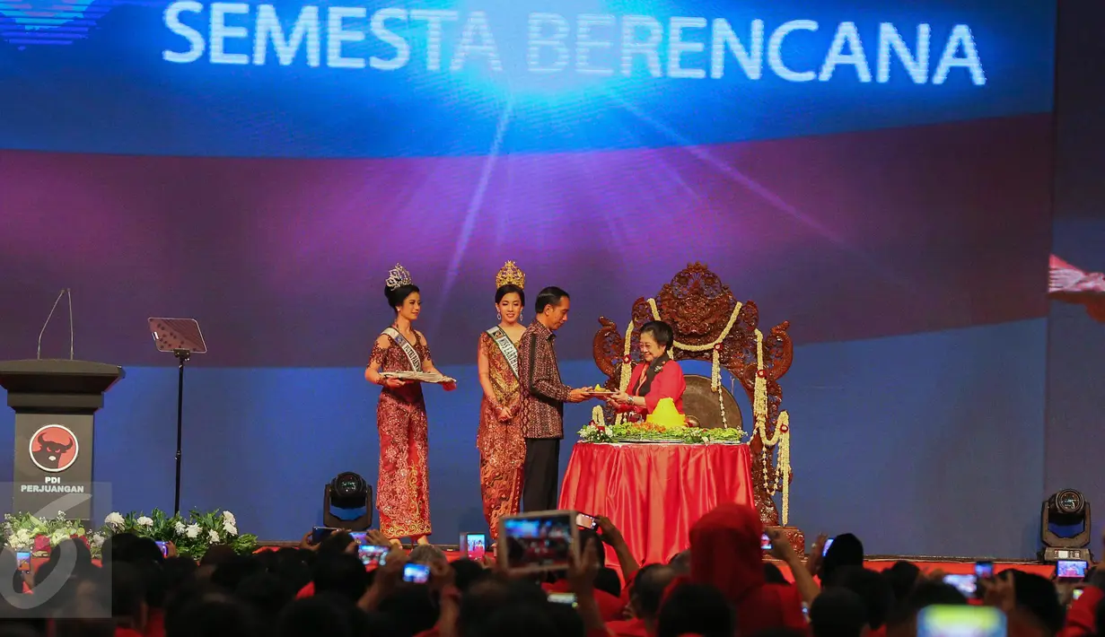 Presiden Jokowi menerima potongan tumpeng dari Megawati saat Rakenas I PDIP, Jakarta, Minggu (10/1/2016). Rakernas tersebut bertajuk 'Mewujudkan Trisakti dengan Pembangunan Nasional Semesta Berencana'. (Liputan6.com/Faizal Fanani)