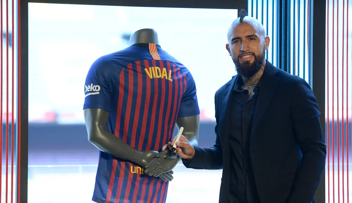 Pemain baru Barcelona, Arturo Vidal berpose usai menandatangani jersey dalam presentasi resminya di Stadion Camp Nou, Barcelona, Spanyol, Senin (6/8). (Josep LAGO/AFP)