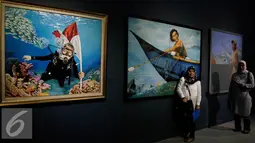 Pengunjung berpose di salah satu lukisan yang dipajang saat pameran seni rupa dan imaji bahari dengan tema "Nautika Bahari" di Galeri Nasional, Jakarta, Selasa (13/9). (Liputan6.com/Johan Tallo)