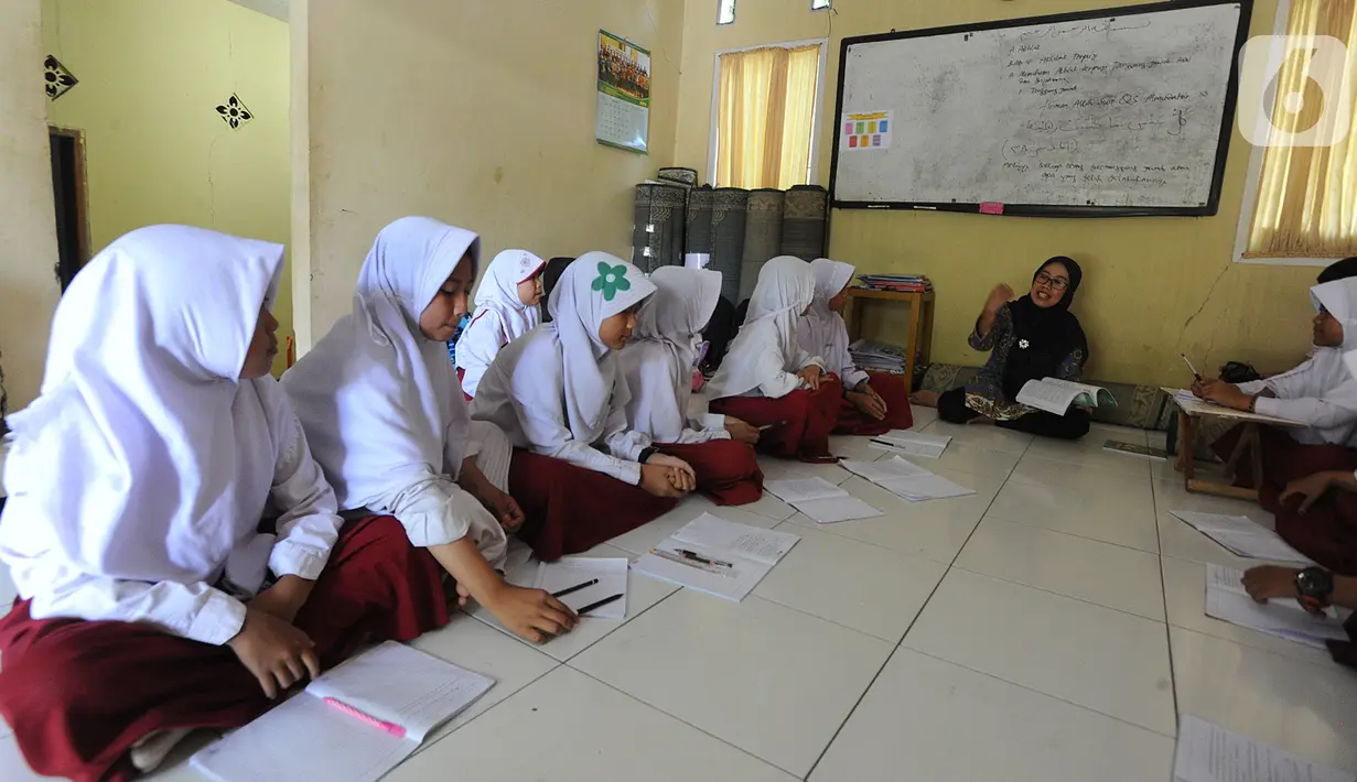 Siswa kelas VI  Madrasah Ibtidaiyah Mathlaul Anwar Ciangsana melakukan proses belajar mengajar tanpa meja dan kursi pada bangunan majelis taklim di Tenjolaya, Bogor, Selasa(22/10/2019).  Kegiatan itu dilakukan karena dua dari lima ruang kelas yang ada sudah rusak dan lapuk. (merdeka.com/Arie Basuki)