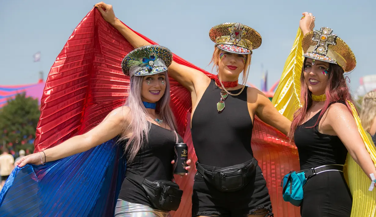 Tiga wanita berkostum unik berpose saat hari ketiga Festival Glastonbury di Worthy Farm, Somerset, Inggris (28/6/2019). Gelombang panas yang melanada bagian-bagian Eropa tidak menyurutkan pengunjung untuk berkumpul di festival ini. (AP Photo/Joel C Ryan)
