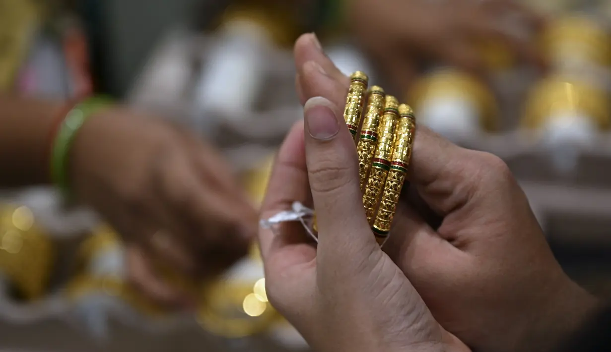 <p>Seorang pelanggan mencoba gelang emas selama festival Hindu 'Akshaya Tritiya', hari keberuntungan dalam kalender Hindu untuk membeli barang-barang berharga, di ruang pamer perhiasan di Chennai, India, Selasa (3/5/2022). Membeli emas adalah kegiatan yang populer di Akshaya Tritiya, karena ini adalah simbol utama kekayaan dan kemakmuran. (Arun SANKAR / AFP)</p>