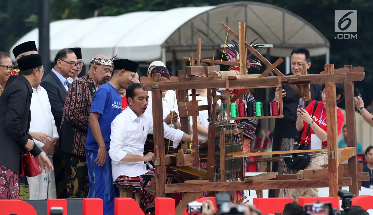 Presiden Joko Widodo mencoba alat penenun kain di Festival Sarung Indonesia 2019, Plaza Tenggara Kompleks GBK, Jakarta, Minggu (3/3). Festival ini untuk menghidupkan kesadaran generasi muda akan kekayaan budaya Indonesia. (Liputan6.com/Helmi Fithriansyah)