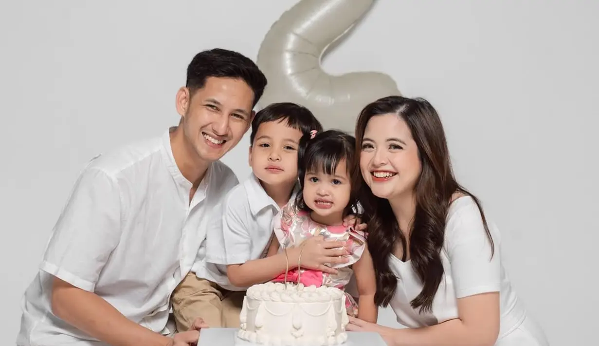 Anak keduanya genap berusia dua tahun, kebahagiaan terpancar jelas di wajah Tasya Kamila dan Randi Bachtiar. Tasya Kamila, Randi, dan si sulung Arassya selaras mengenakan busana putih, sementara Shafanina mengenakan dress simpel floral warna merah muda. Rambut gadis kecil yang akrab disapan Shanin itu dikepang dua sehingga membuatnya terlihat menggemaskan. (Liputan6.com/IG/@tasyakamila)