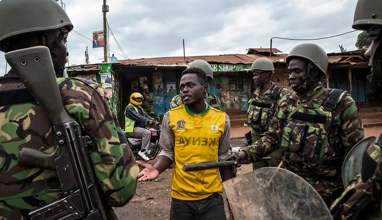 Polisi Kenya menginterogasi demonstran di daerah Kawangware di Nairobi, Kenya (10/8). Presiden Kenya Uhuru Kenyatta menang dalam pemilihan presiden, Jumat (11/8/2017) waktu setempat. (AFP Photo/Patrick Meinhardt)